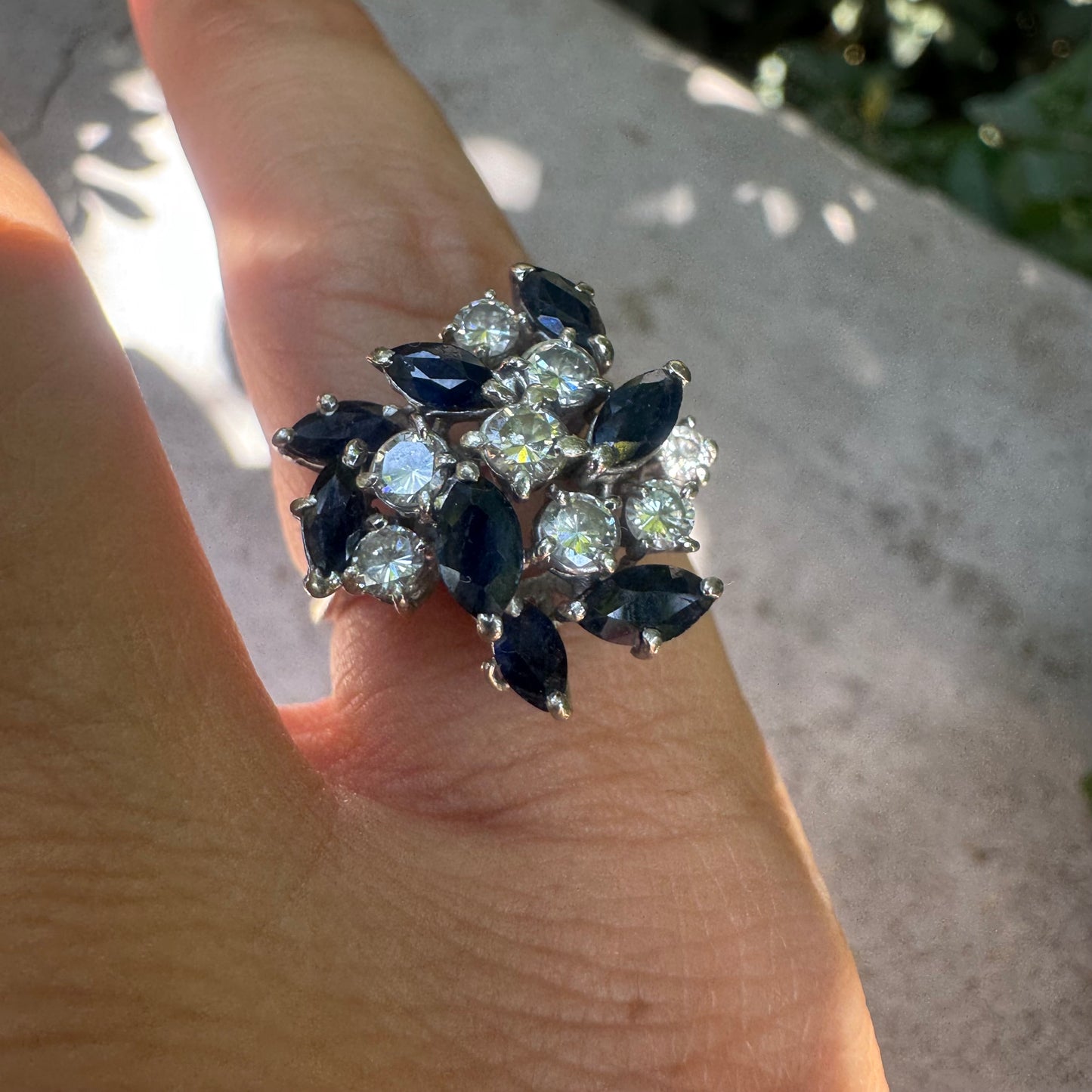 18K gold cluster ring featuring marquise-cut blue sapphires and round brilliant Diamonds arranged in a floral design.