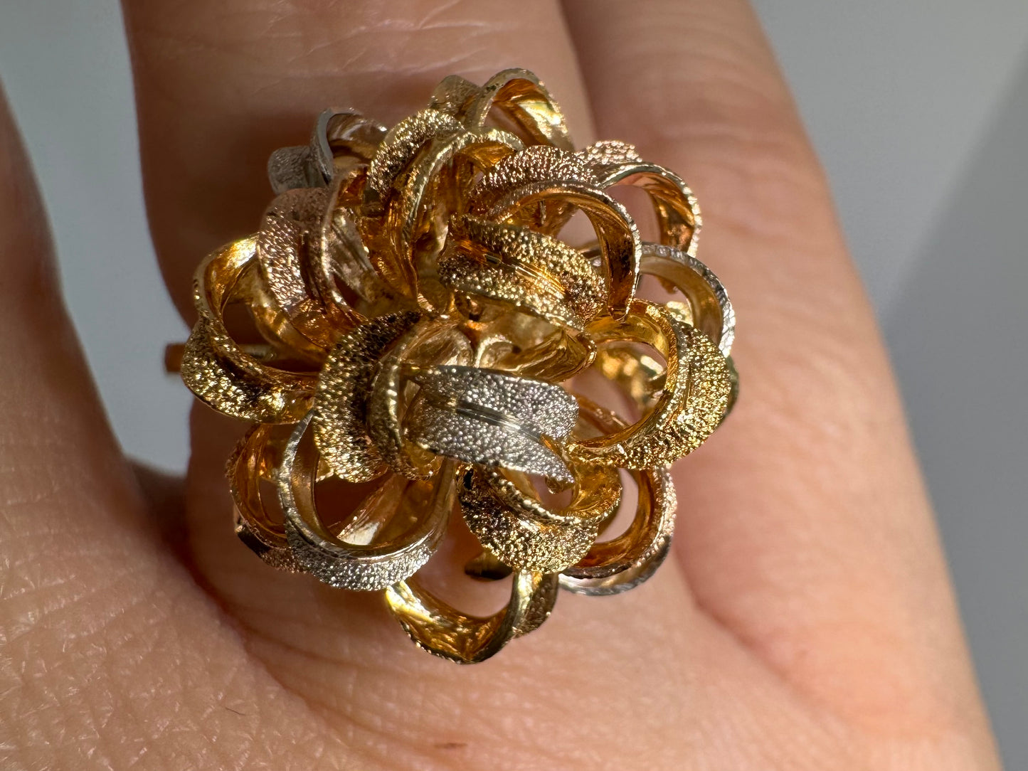 18K gold ring set with intricately textured loops in yellow, white, and rose gold, forming a bold floral-inspired sculptural design.