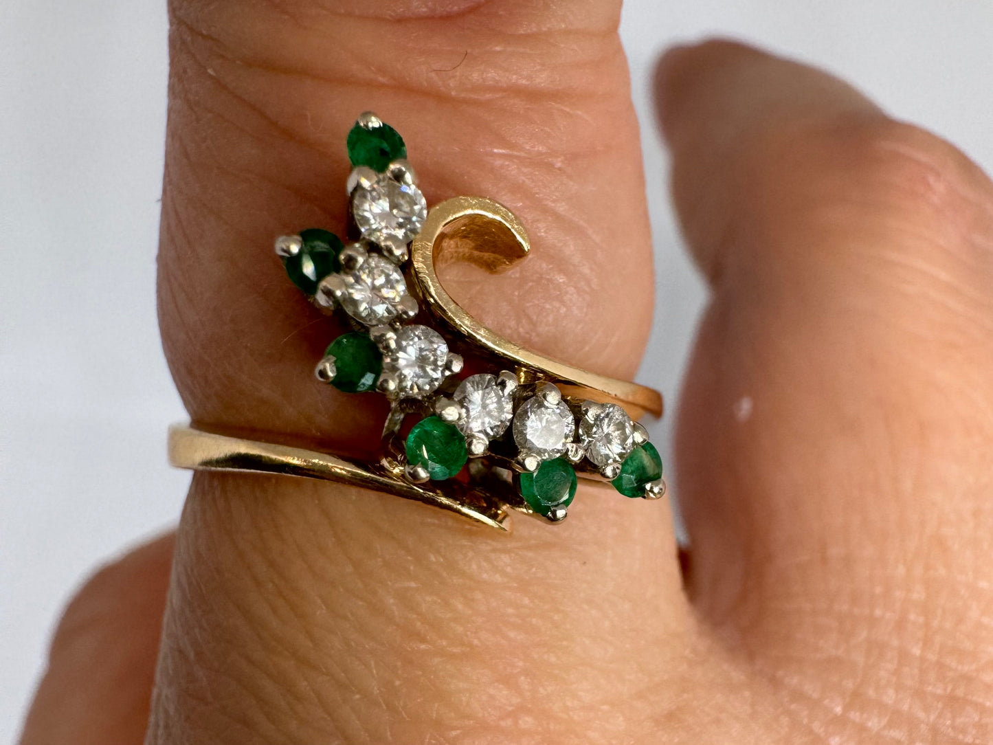 14K gold open ring featuring a delicate swirl set with Emeralds and brilliant-cut Diamonds