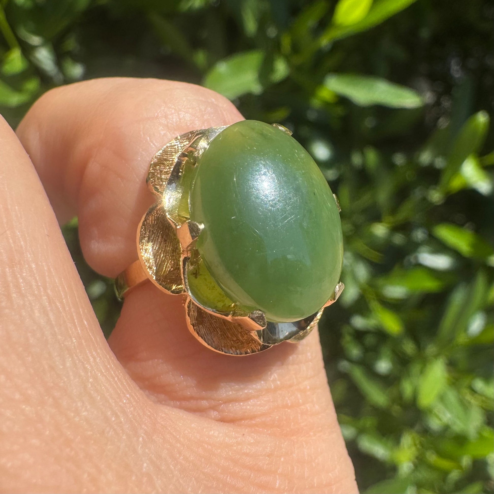 טבעת זהב צהוב 14 קראט, משובצת אבן ג׳ייד (ירקן) ירוקה בליטוש קבושון חלק, בעיצוב פרחוני עדין ומלא אופי.