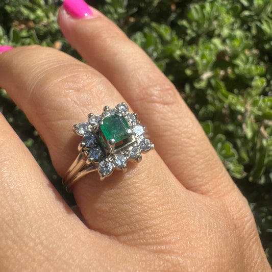 18K gold ring set with a vibrant square-cut Emerald surrounded by a sparkling halo of Diamonds.