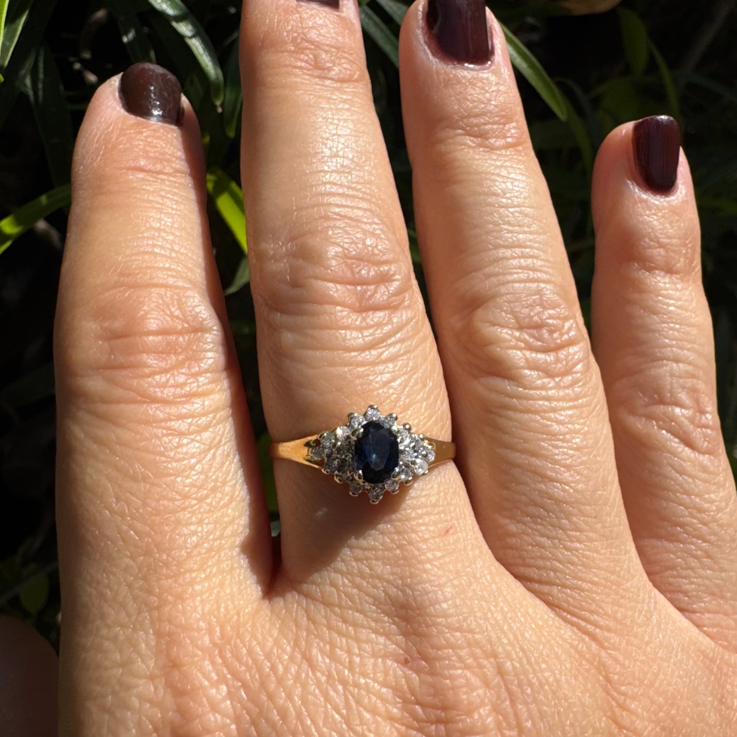 14K gold ring set with an oval blue Sapphire surrounded by sparkling Diamonds