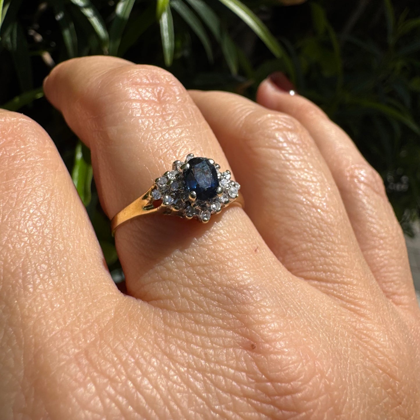 14K gold ring set with an oval blue Sapphire surrounded by sparkling Diamonds