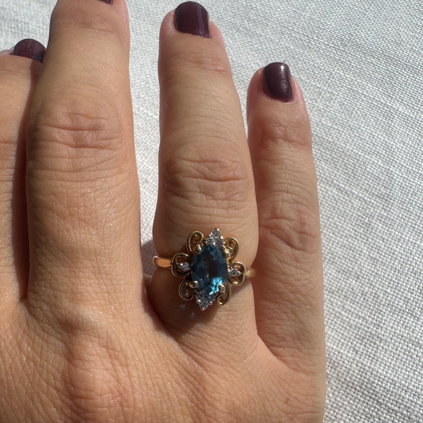 18K gold ring featuring an oval-cut Blue Topaz at the center, accented by sparkling side Diamonds and elegant scroll details.