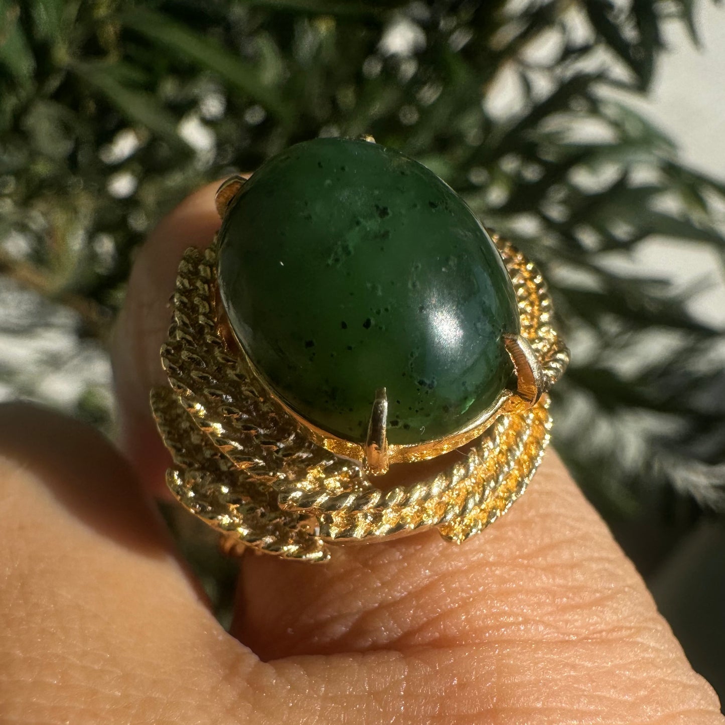 14K gold ring set with a deep green Jade set in a textured gold frame.