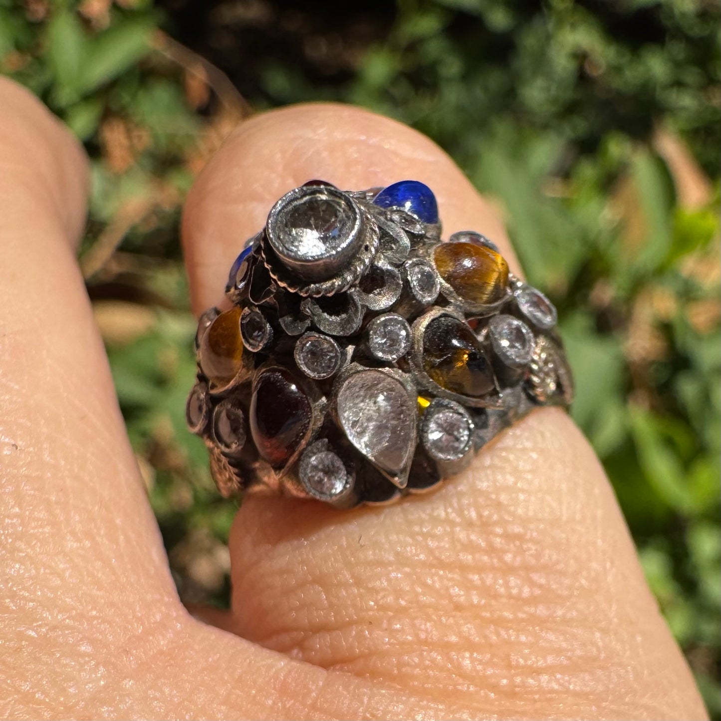 14K gold ring set with a central transparent gemstone surrounded by a vibrant mosaic of colorful gemstones -set in an ornate, handcrafted design