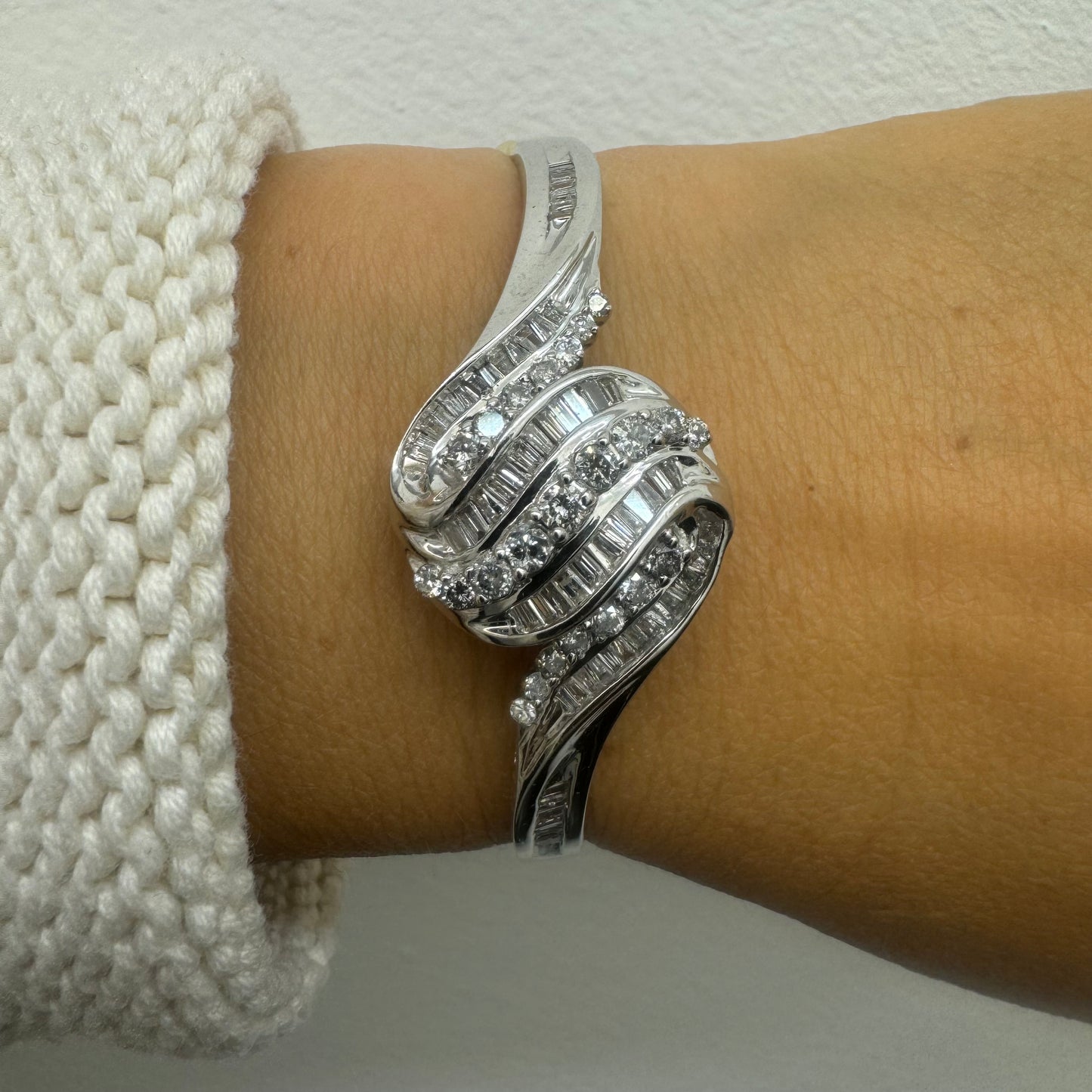 צמיד מרהיב מזהב לבן 14 קראט, בעיצוב גלים דינמי המשובץ בשיבוץ מרוכב של יהלומים עגולים ובחיתוך באגט.