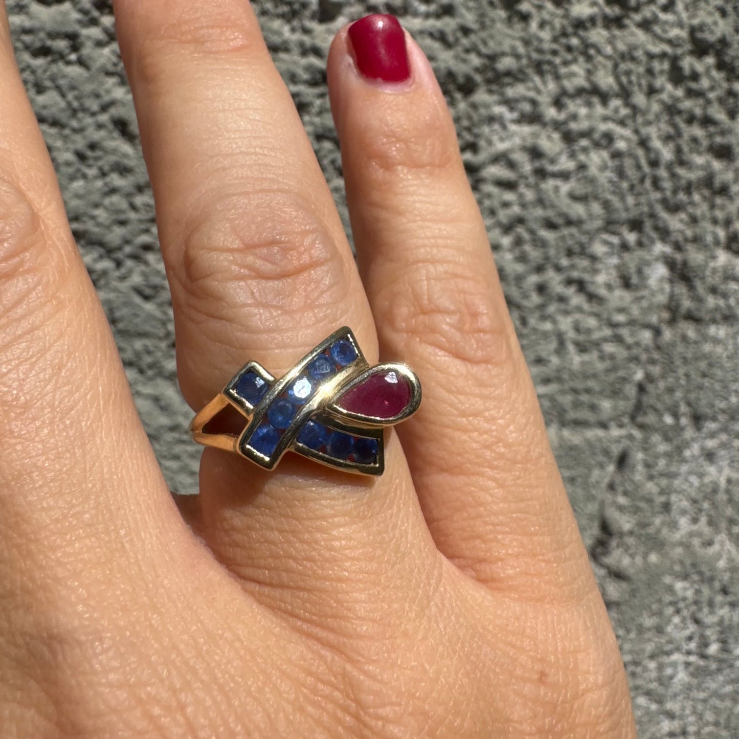 10K gold ring set with a pear-shaped Ruby and deep blue Sapphires in a geometric design.