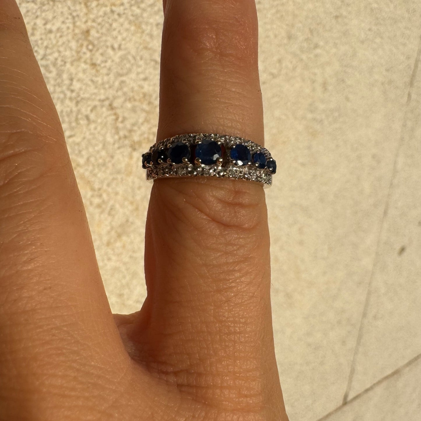 18K gold ring set with deep blue sapphires in a classic round cut, framed by two shimmering rows of brilliant Diamonds.