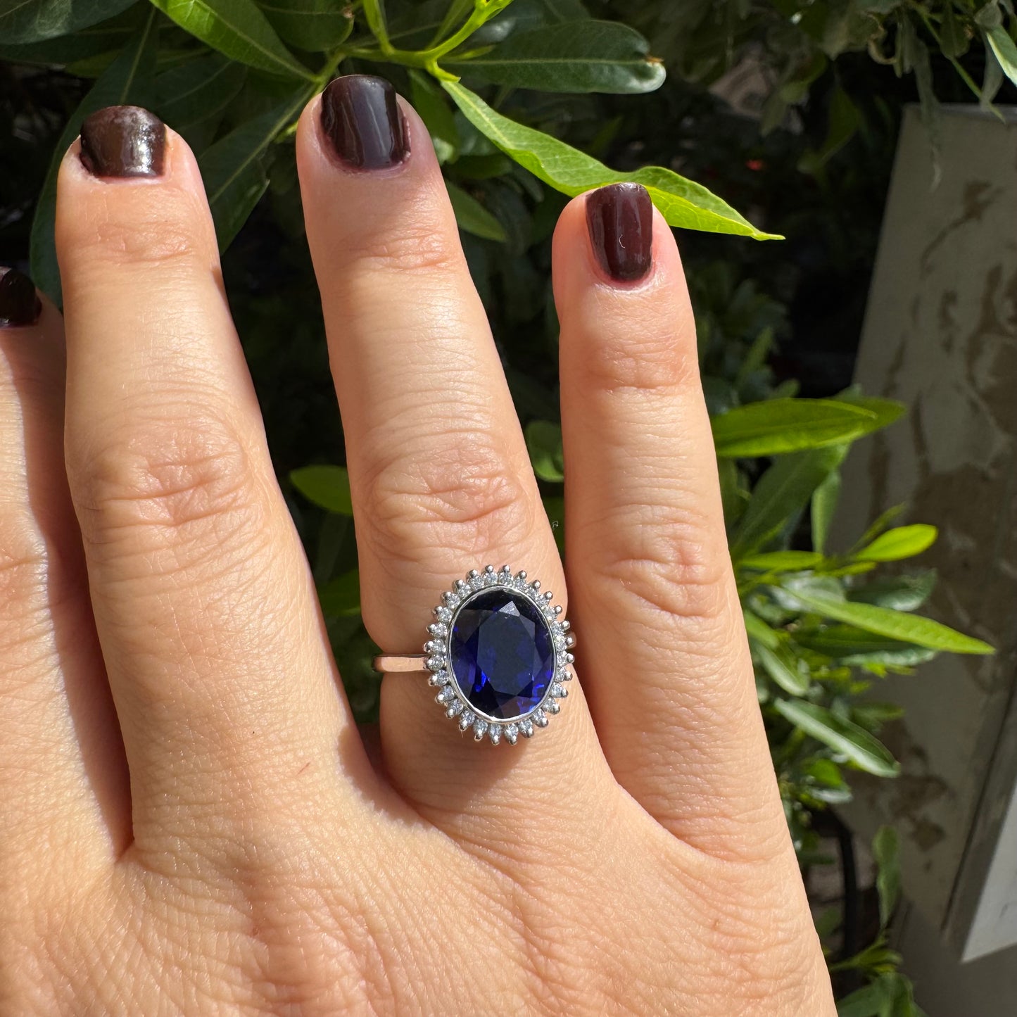 14K gold ring set with a deep blue oval Sapphire surrounded by a halo of sparkling Diamonds