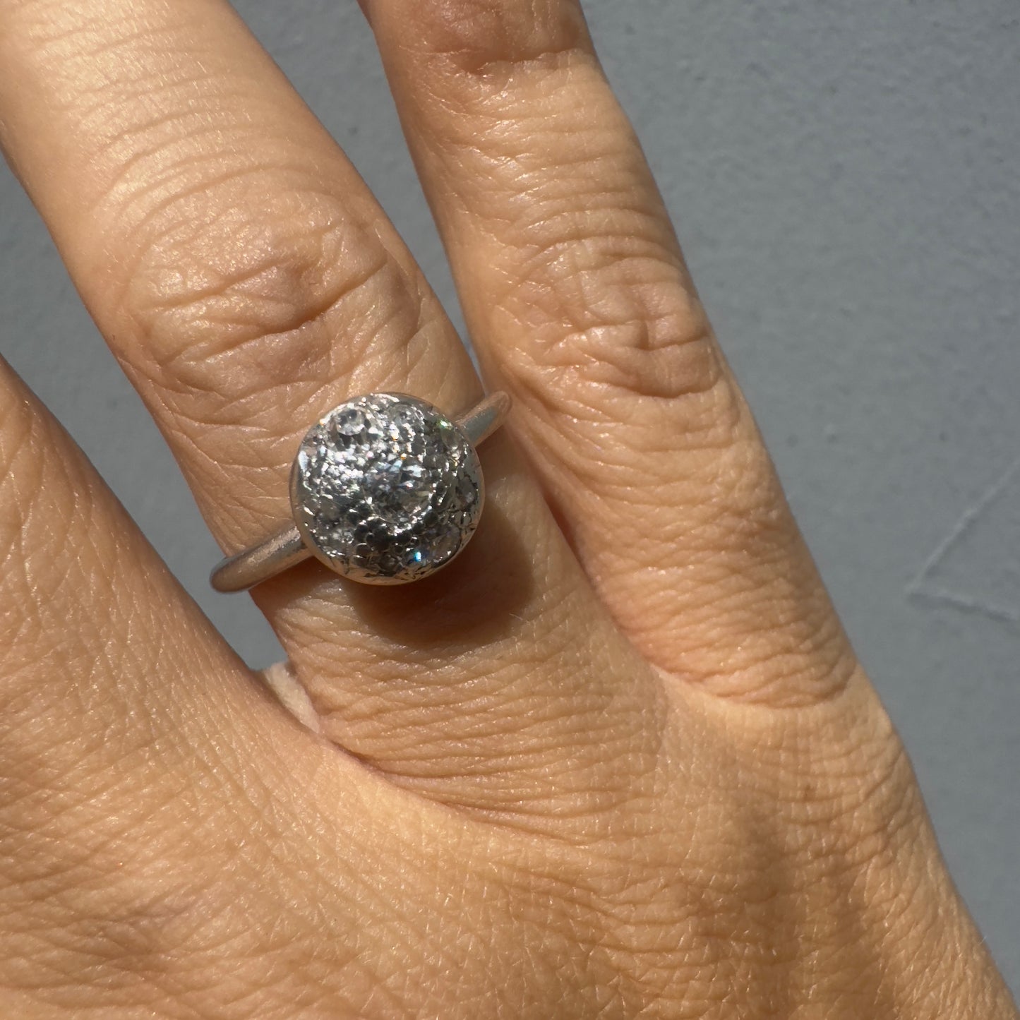 טבעת פלטינה עם אשכול עגול של יהלומים נוצצים במרכז, ליצירת מראה מודגש ואלגנטי