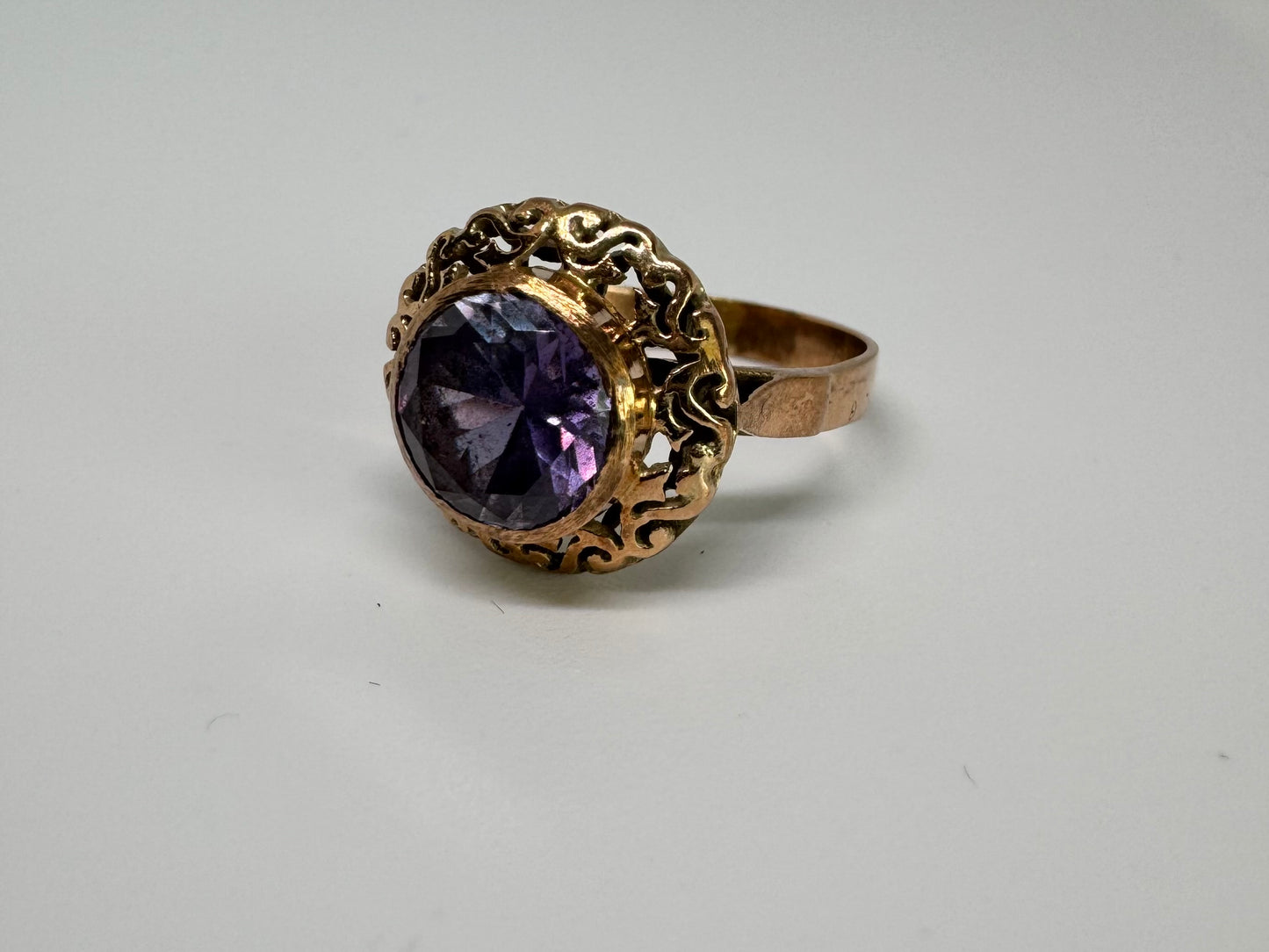 14K gold ring set with a large round-cut Tanzanite framed by an ornate filigree bezel