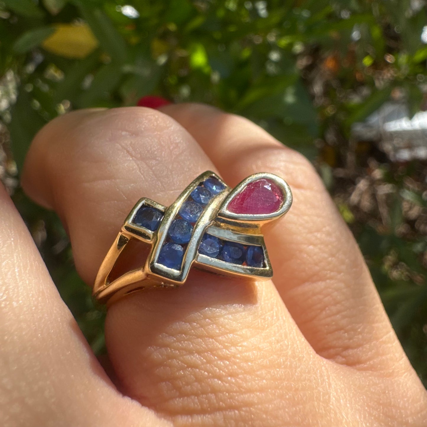 10K gold ring set with a pear-shaped Ruby and deep blue Sapphires in a geometric design.