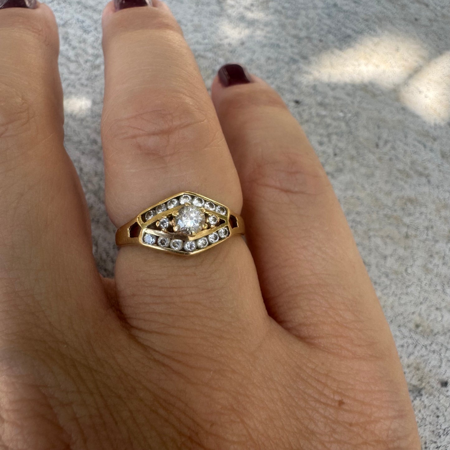 18K gold ring set with a central round Diamond, surrounded by rows of Diamonds in a decorative setting.