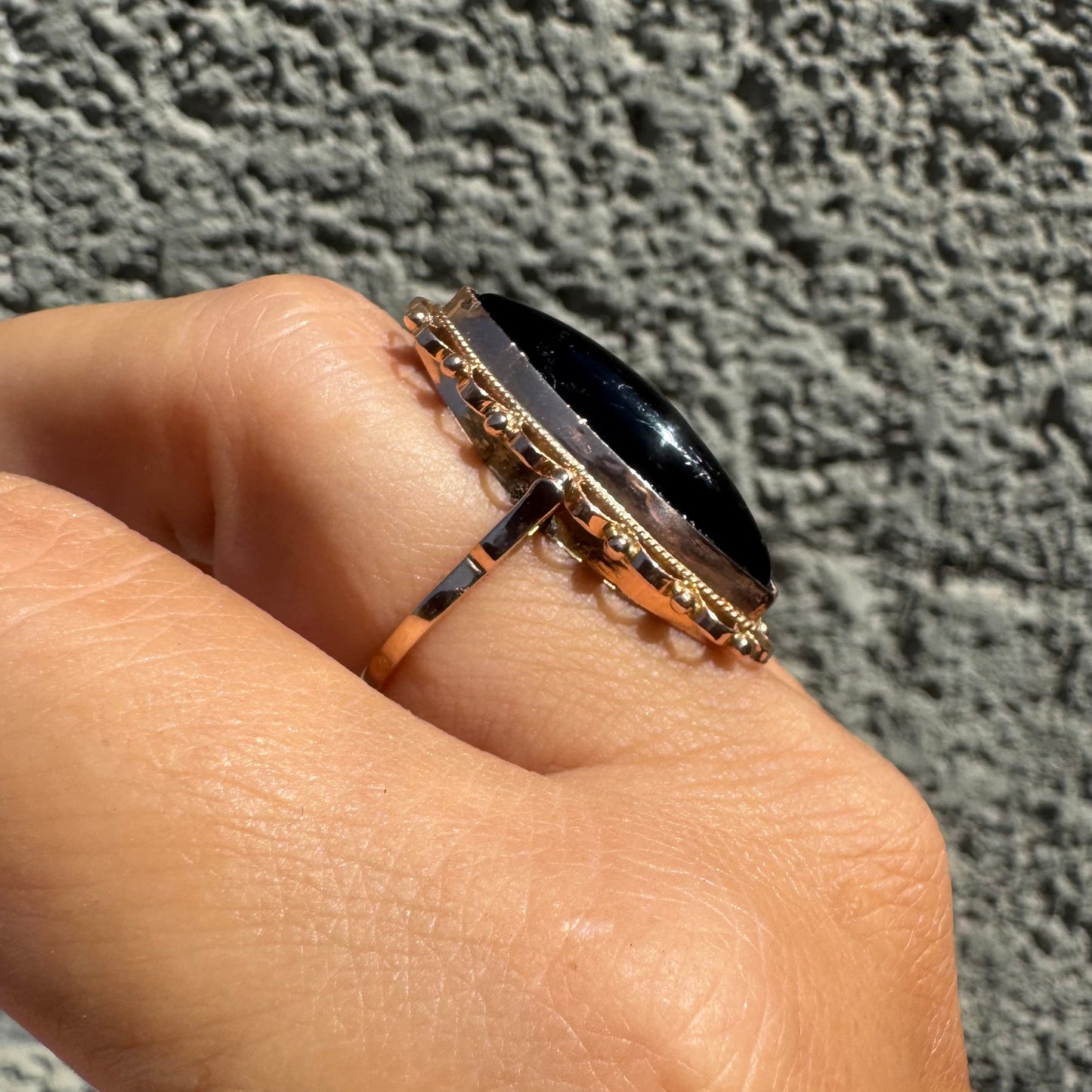 14K gold ring featuring a long marquise-shaped black Onyx stone, framed with delicate decorative details around the setting.