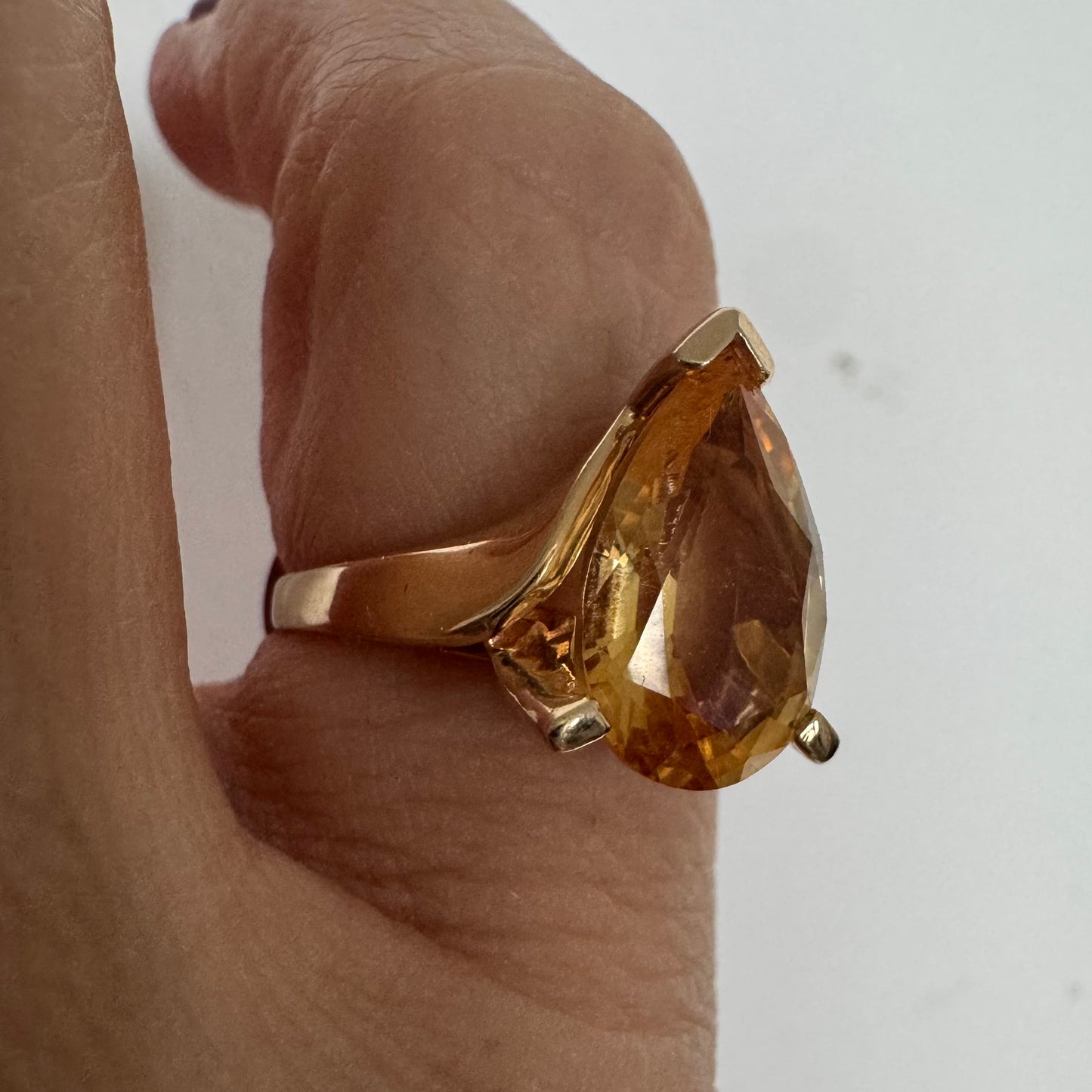 טבעת זהב צהוב 14 קראט משובצת באבן סיטרין גדולה בחיתוך טיפה, עם זהב שמחבק אותה בצורה פתוחה ומודרנית.