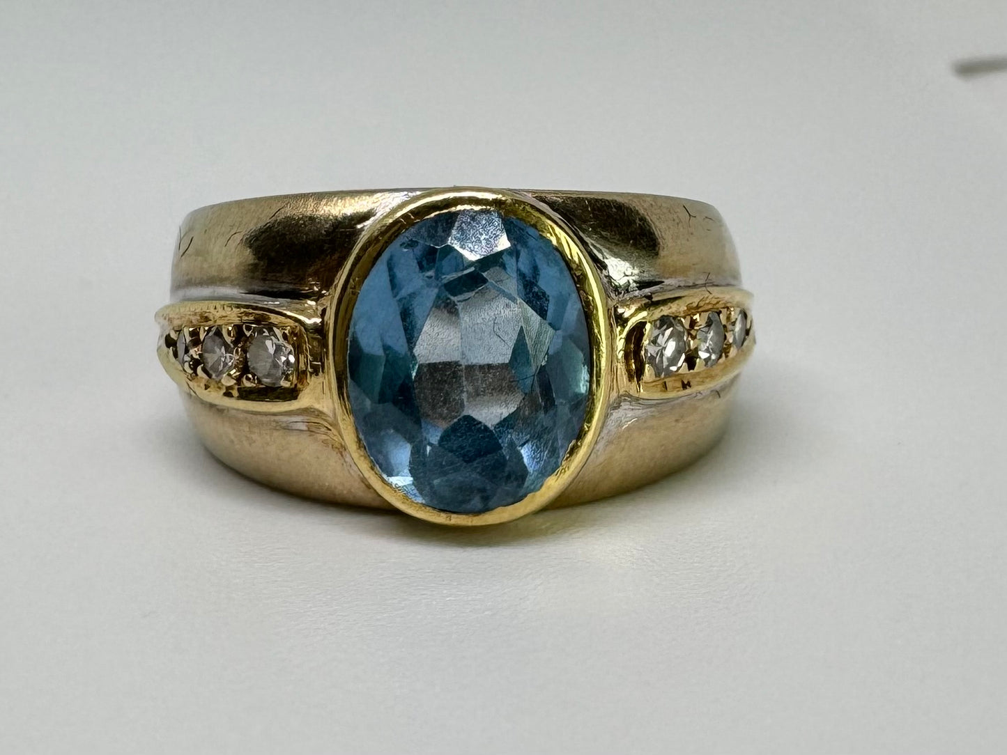 14K gold ring set with a luminous Blue Topaz at its center, accented by delicate side Diamonds