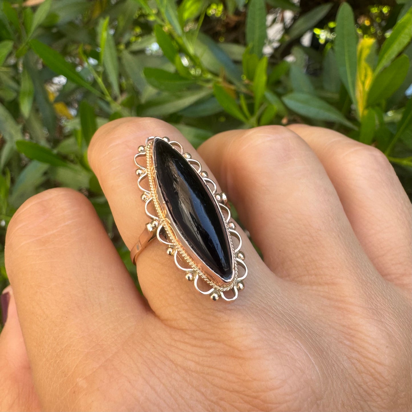 14K gold ring featuring a long marquise-shaped black Onyx stone, framed with delicate decorative details around the setting.