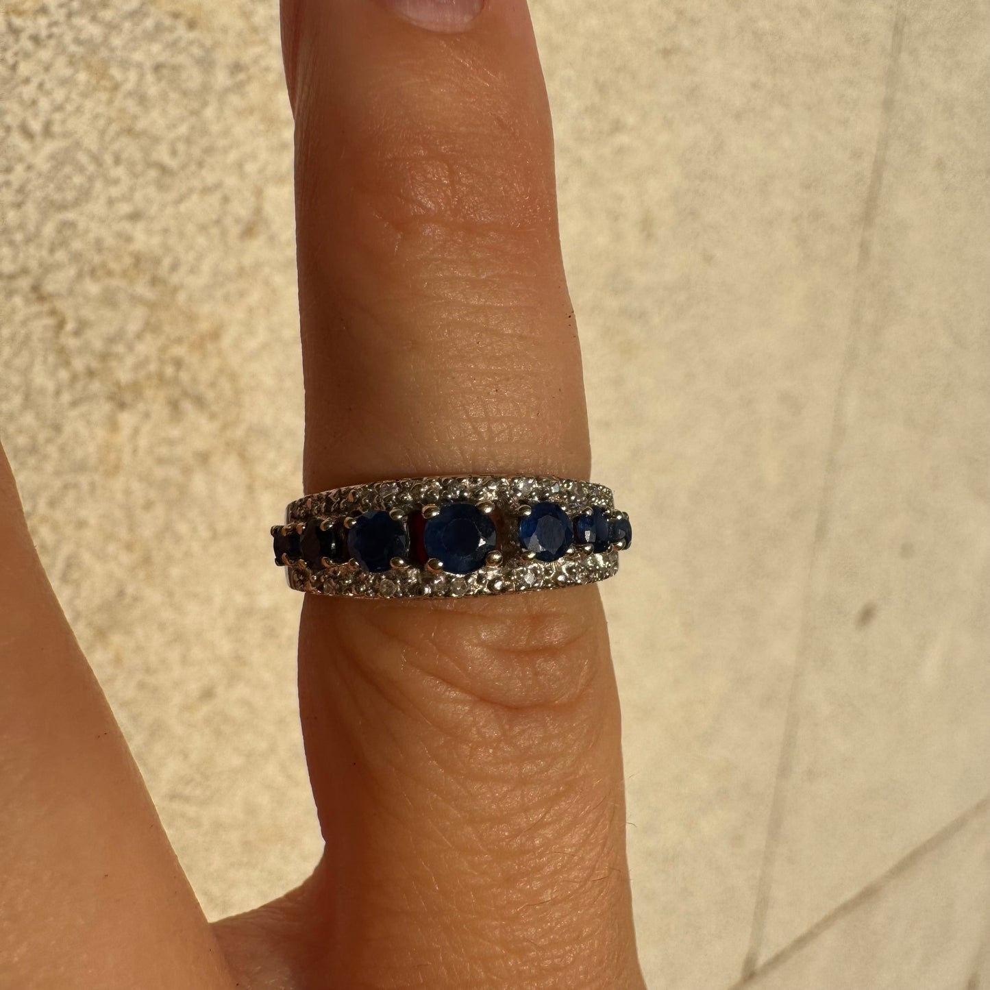 18K gold ring set with deep blue sapphires in a classic round cut, framed by two shimmering rows of brilliant Diamonds.