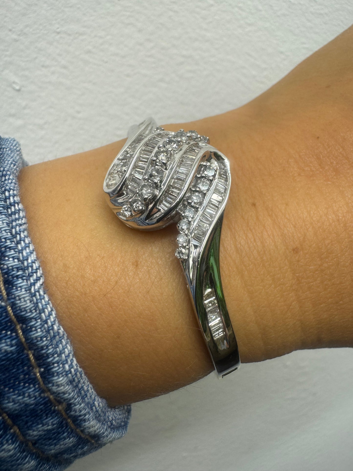 צמיד מרהיב מזהב לבן 14 קראט, בעיצוב גלים דינמי המשובץ בשיבוץ מרוכב של יהלומים עגולים ובחיתוך באגט.