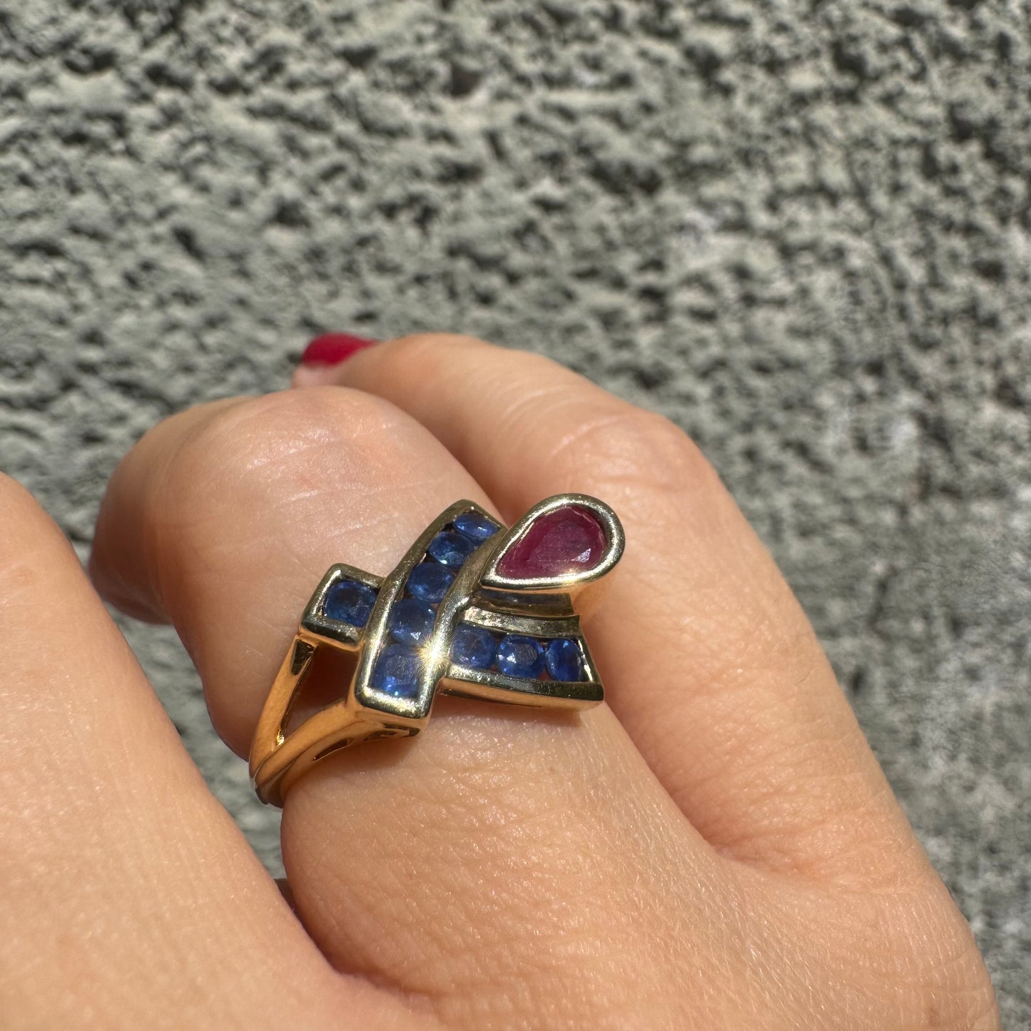 10K gold ring set with a pear-shaped Ruby and deep blue Sapphires in a geometric design.