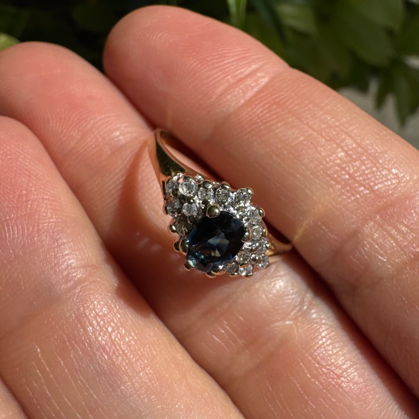 14K gold ring set with an oval blue Sapphire surrounded by sparkling Diamonds