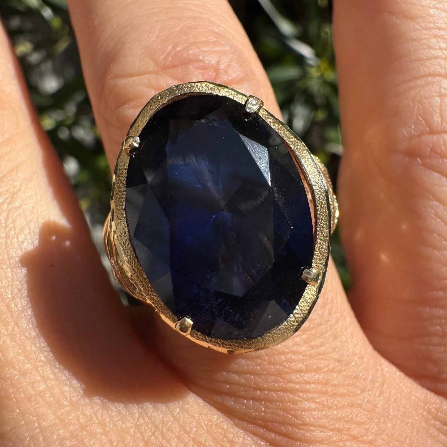 14K gold ring set with a deep navy-blue oval Sapphire in a dramatic openwork setting