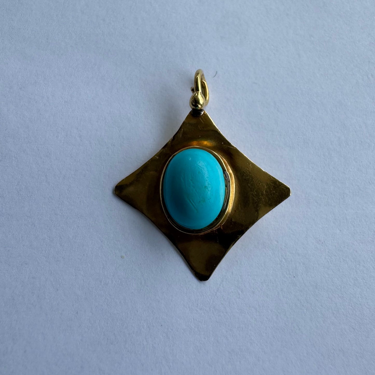 תליון זהב 14 קראט בעיצוב גאומטרי ייחודי, משובץ אבן טורקיז קבושון בגוון תכלת חי.