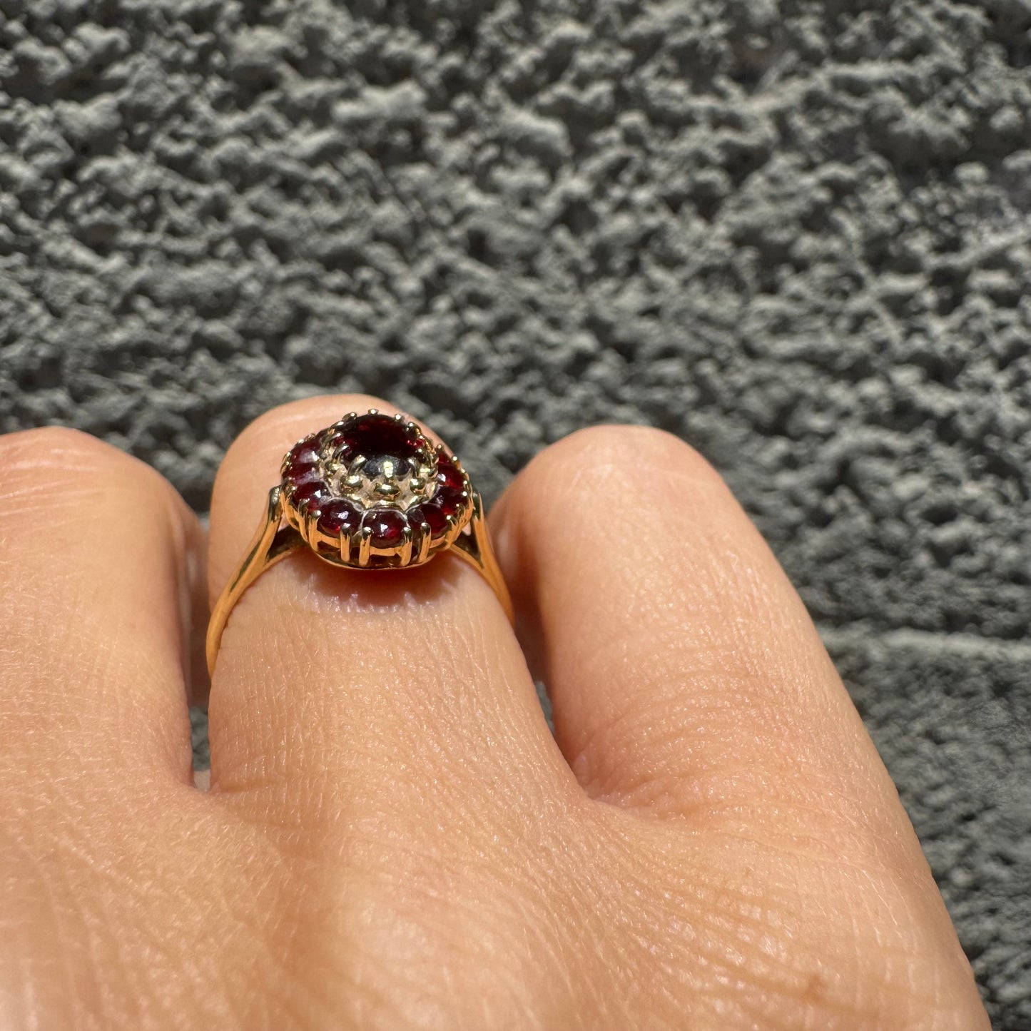 18K gold ring set with an oval garnet center stone, surrounded by smaller garnets