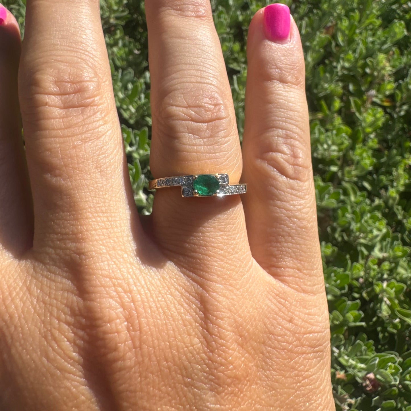 18K gold ring set with an oval green Emerald at the center, accented with sparkling Diamonds along the band.