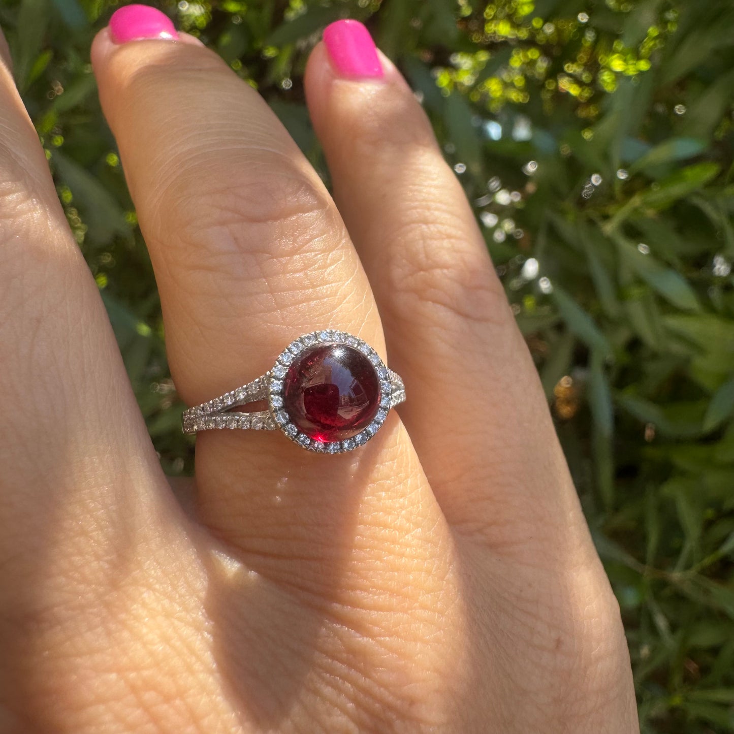 14K gold ring set with a deep red cabochon Garnet, surrounded by a halo of sparkling Diamonds