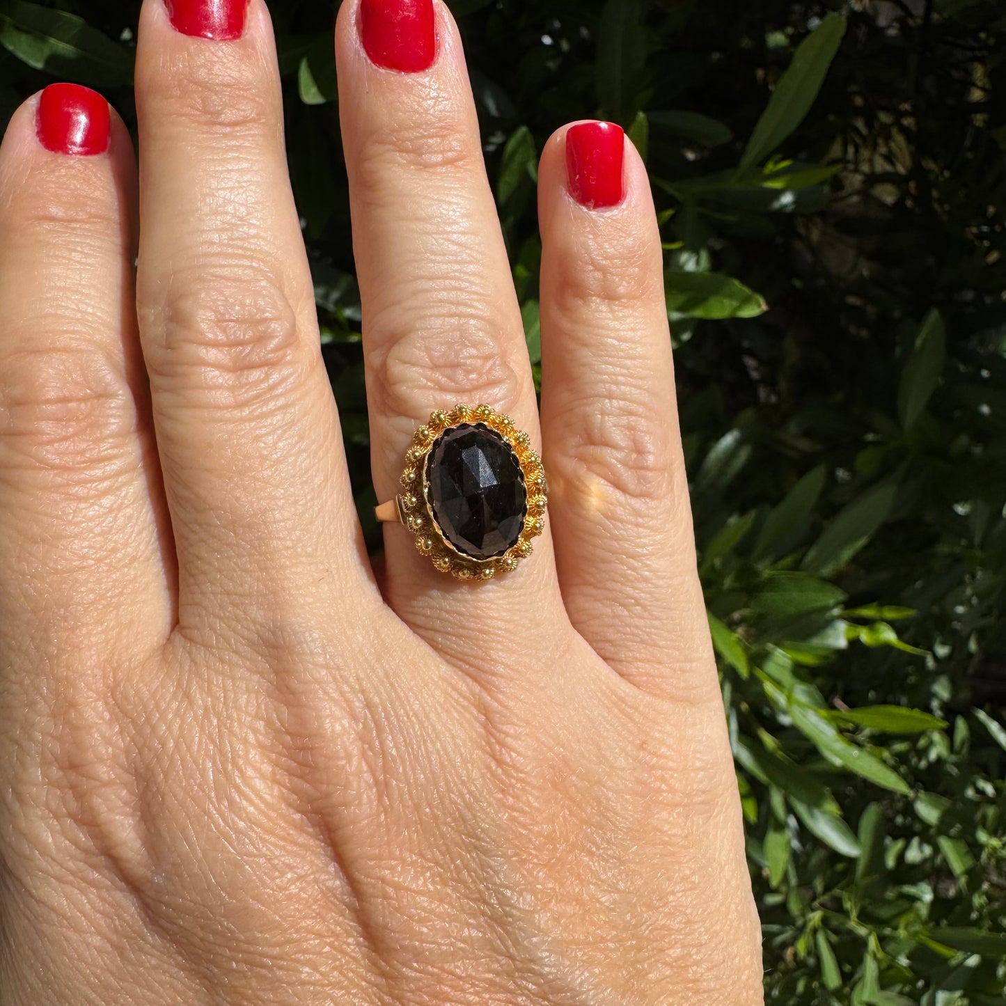 14K gold ring set with a large Garnet surrounded by delicate gold details