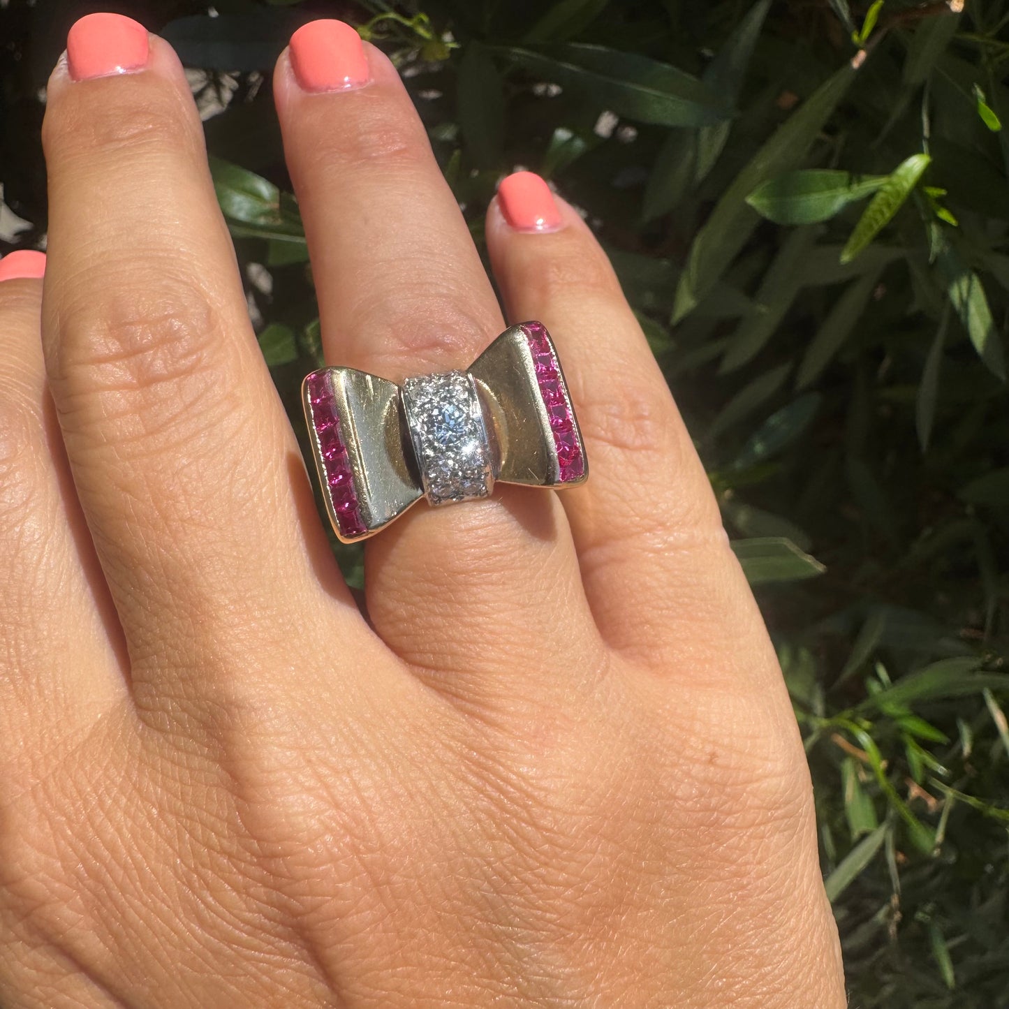 18K gold bow-shaped ring set with pavé Diamonds at the center and rows of square-cut Rubies on the sides.