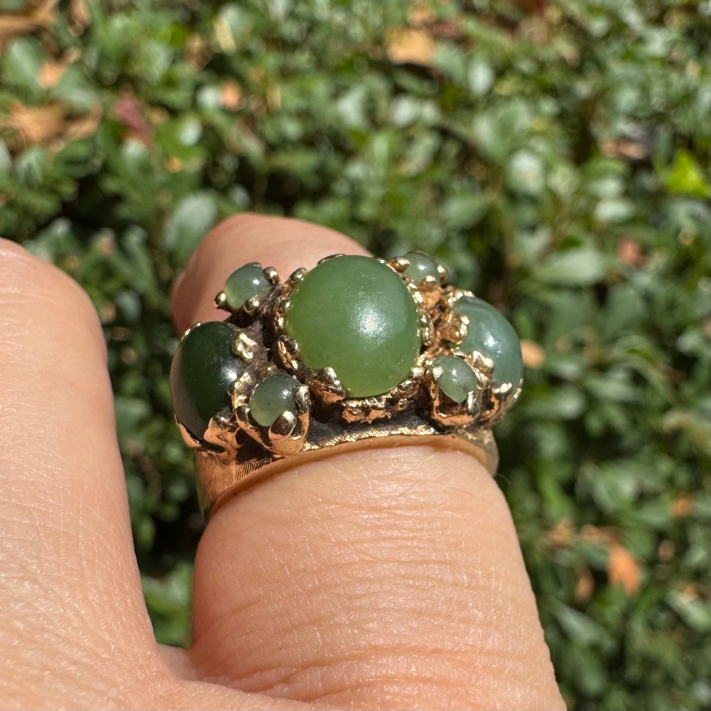 14K gold ring set with a central oval green Jade cabochon, framed by additional Jade stones in varying shades and sizes
