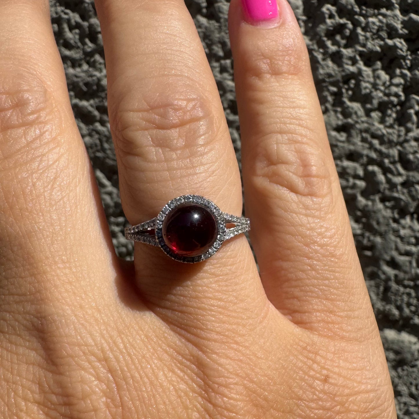 14K gold ring set with a deep red cabochon Garnet, surrounded by a halo of sparkling Diamonds