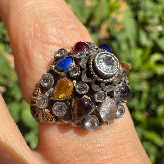 טבעת זהב צהוב 14 קראט משובצת אבן מרכזית שקופה וסביבה פסיפס צבעוני של אבני חן צבעוניות: גרנט, עין הנמר, ואבני חן נוספות, בשיבוץ ידני בסגנון עתיק