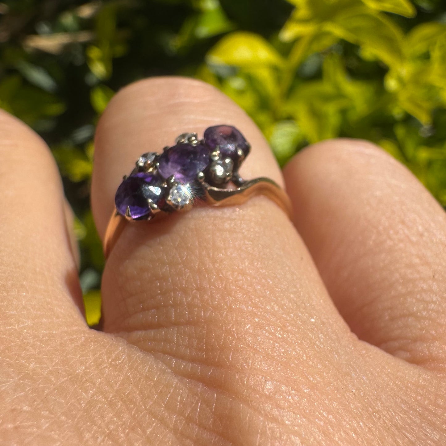 14K gold ring set with three round purple amethysts, accented by small sparkling Diamonds.