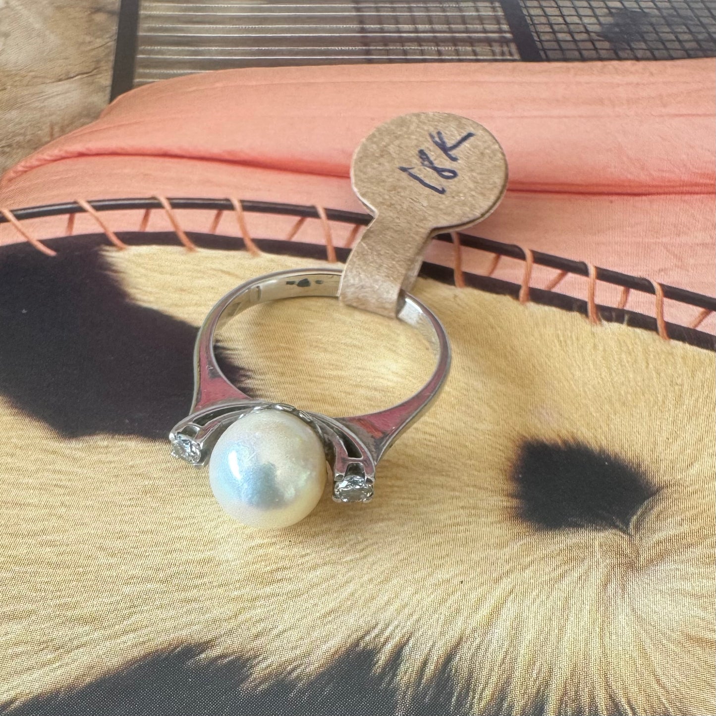 18K gold ring featuring a round Pearl at the center, flanked by two Diamonds.