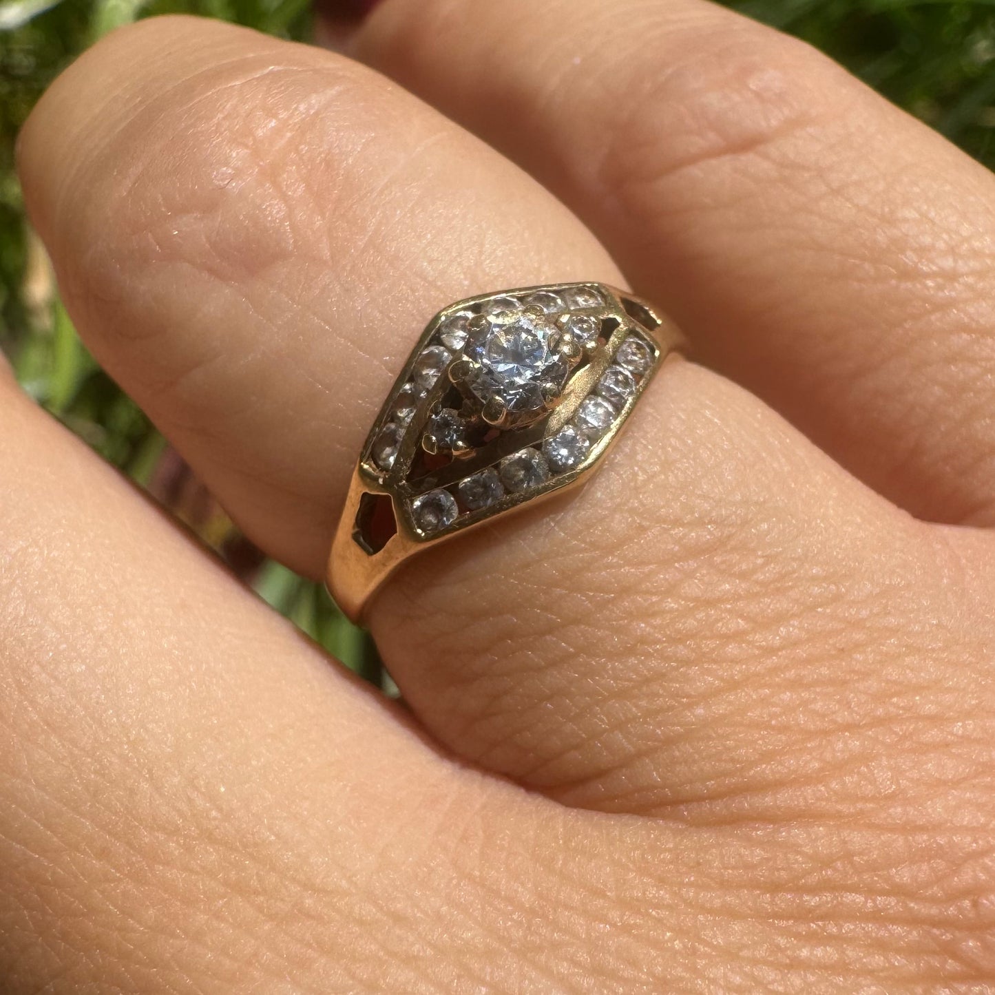 18K gold ring set with a central round Diamond, surrounded by rows of Diamonds in a decorative setting.