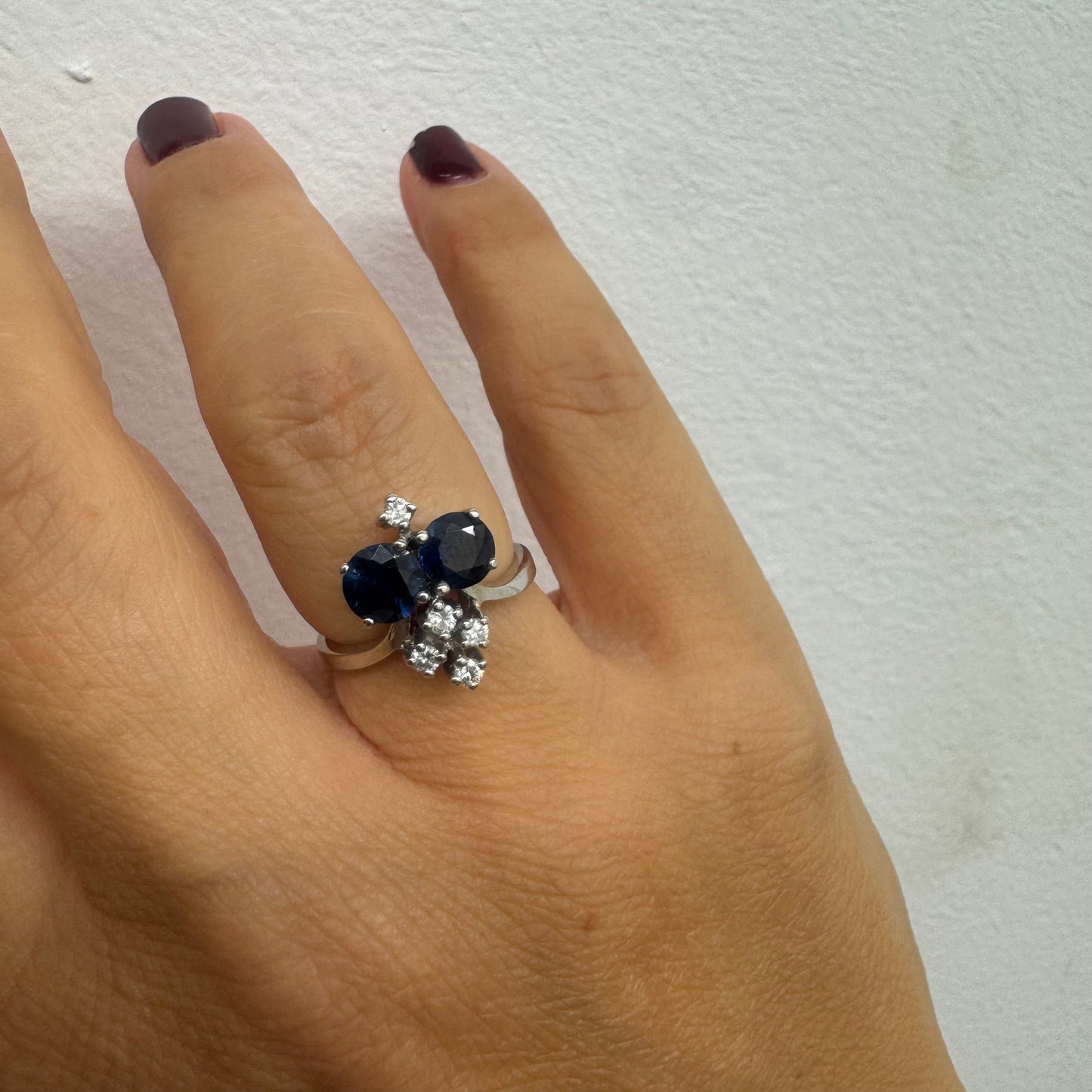 14K gold ring set with two deep blue oval Sapphires accented by clusters of brilliant white Diamonds.