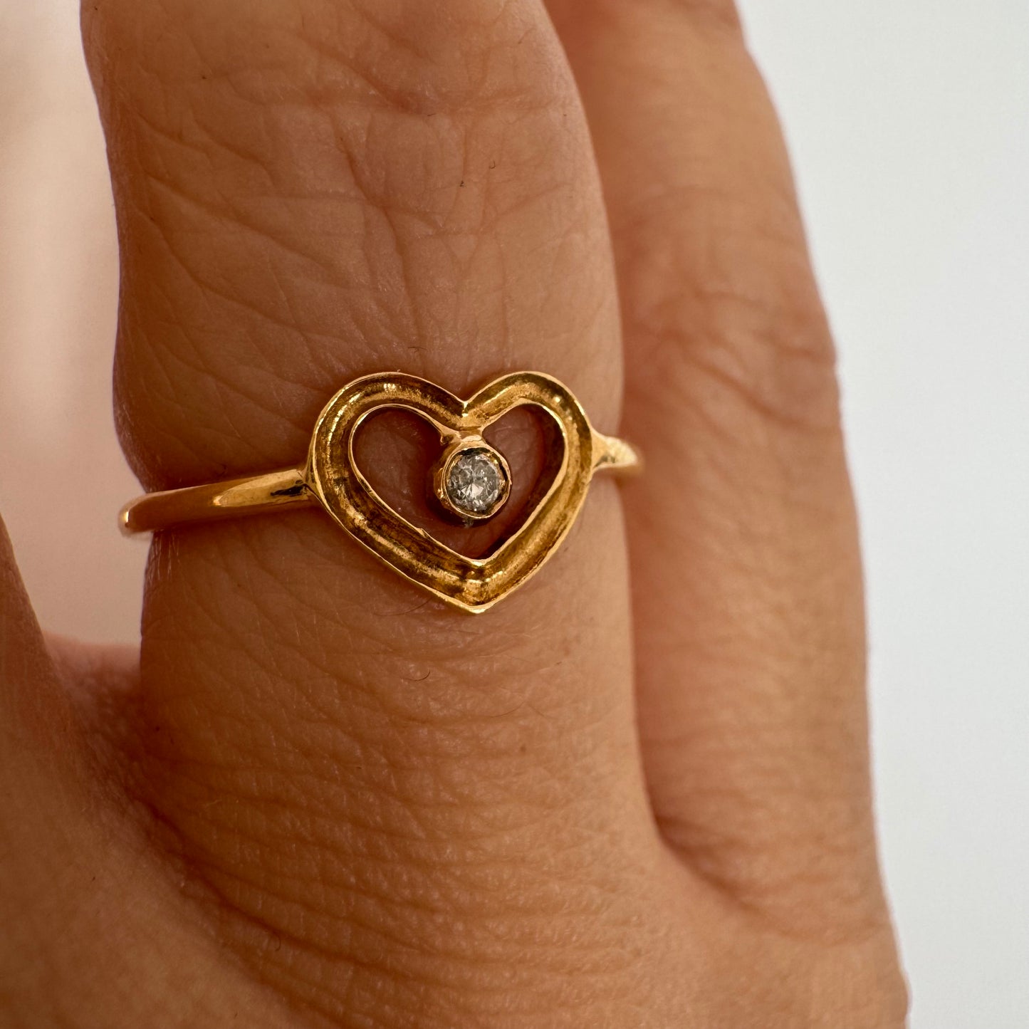 טבעת זהב 14 קראט בעיצוב לב פתוח ועדין, עם יהלום קטן במרכז שמוסיף נקודת אור אלגנטית.
