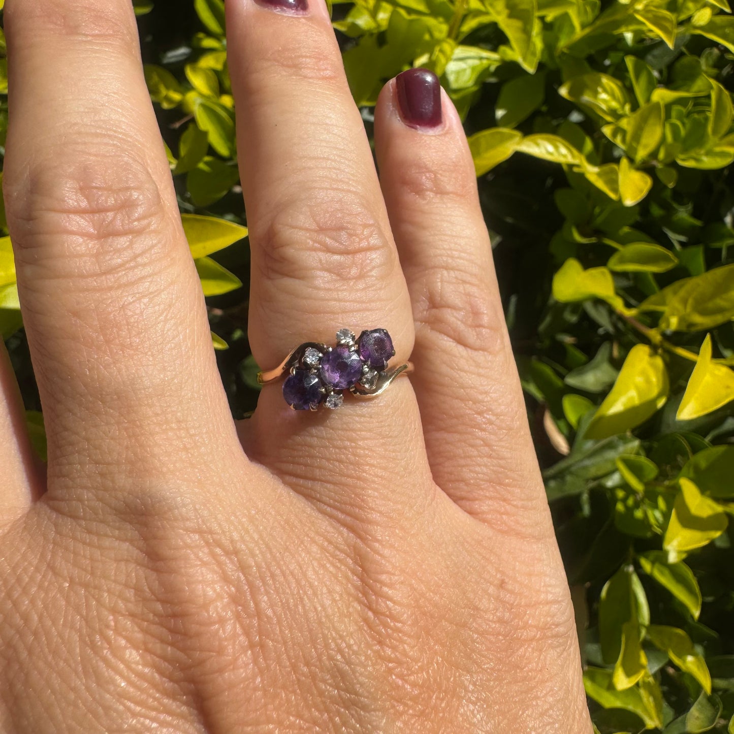 14K gold ring set with three round purple amethysts, accented by small sparkling Diamonds.