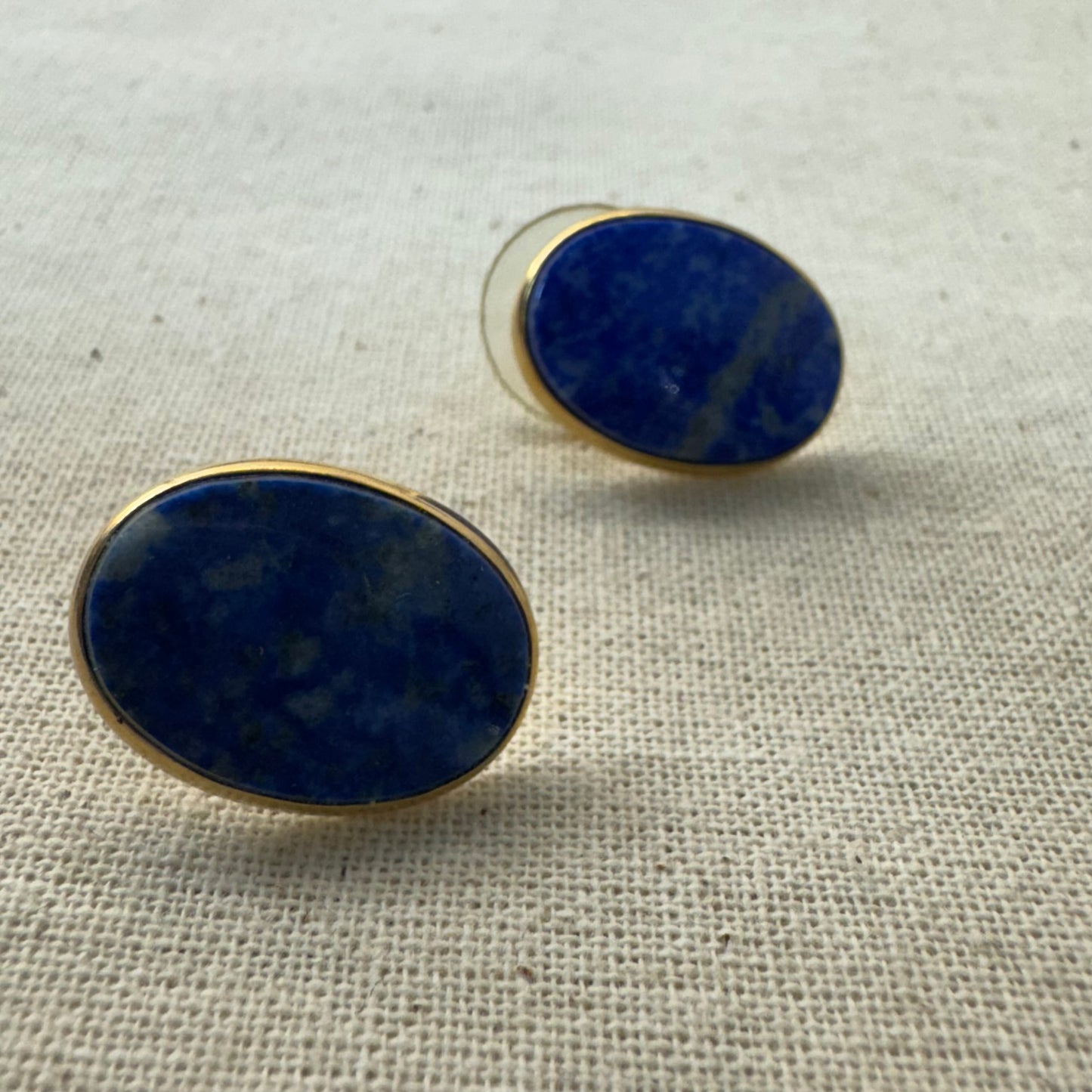 14K gold stud earrings set with polished oval Lapis Lazuli stones in a sleek gold bezel setting.