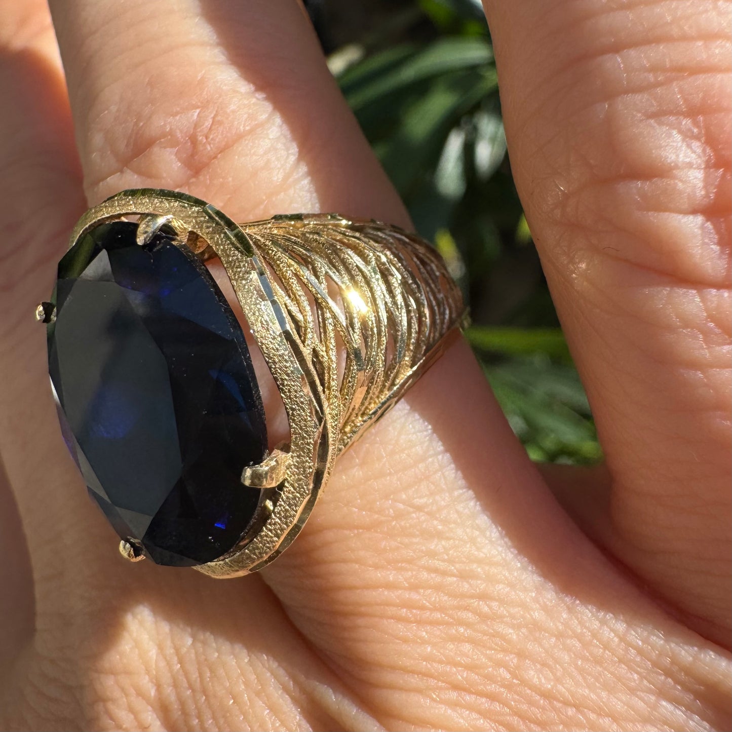 14K gold ring set with a deep navy-blue oval Sapphire in a dramatic openwork setting