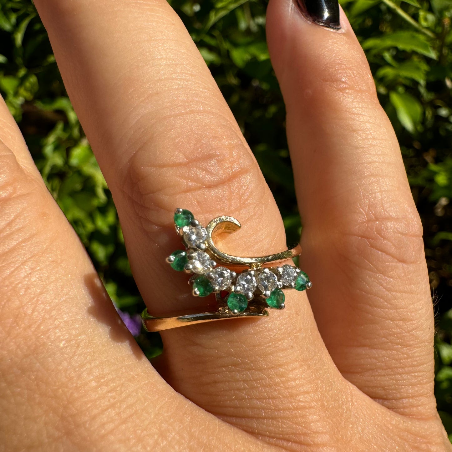14K gold open ring featuring a delicate swirl set with Emeralds and brilliant-cut Diamonds