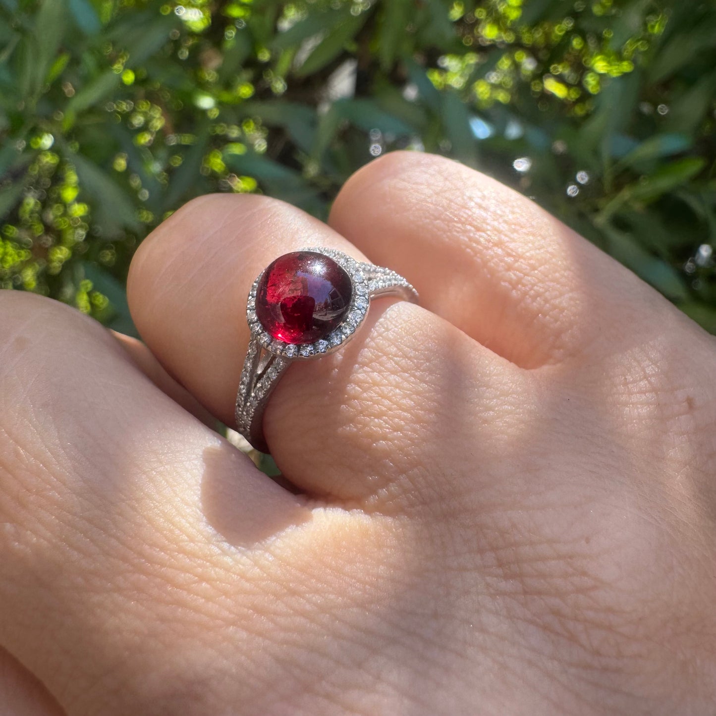 14K gold ring set with a deep red cabochon Garnet, surrounded by a halo of sparkling Diamonds