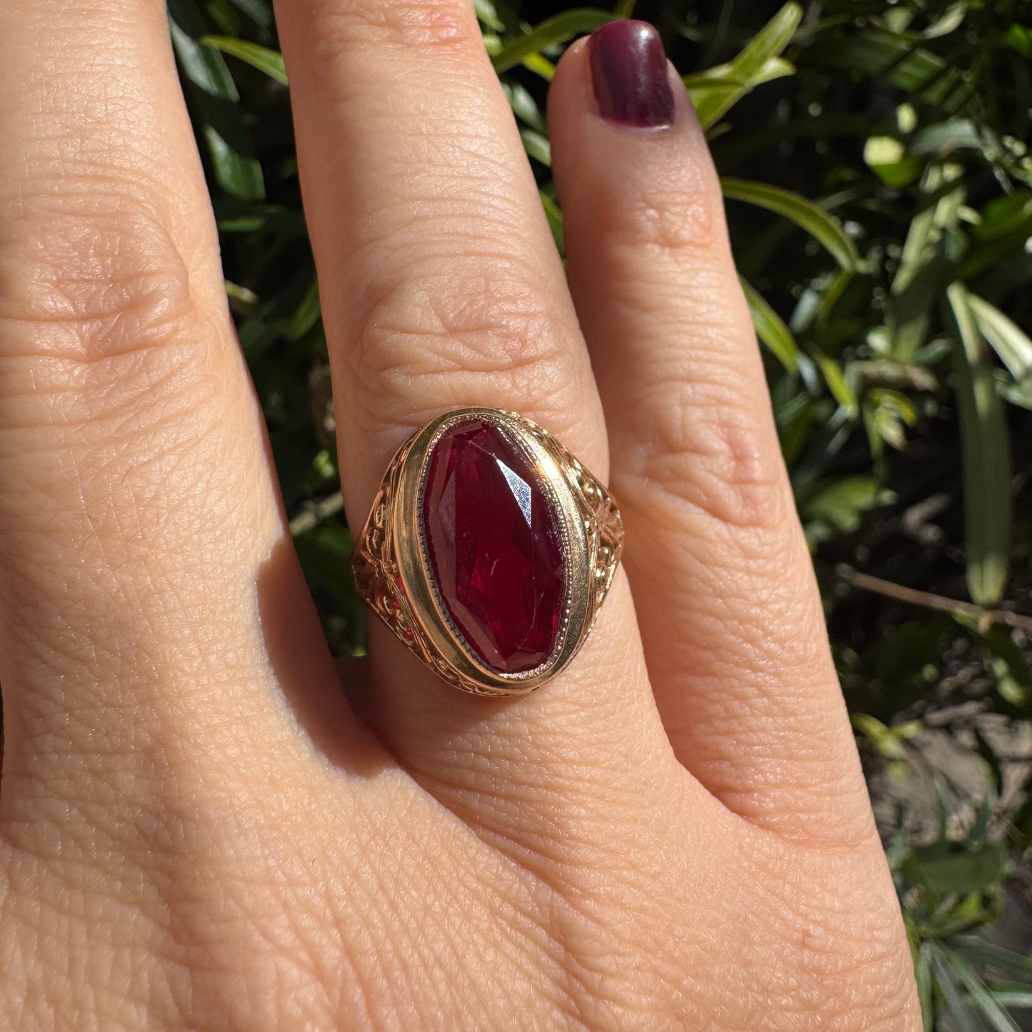 14K gold ring crowned with a vivid oval-cut Ruby, framed in an ornate bezel and accented by intricate filigree details