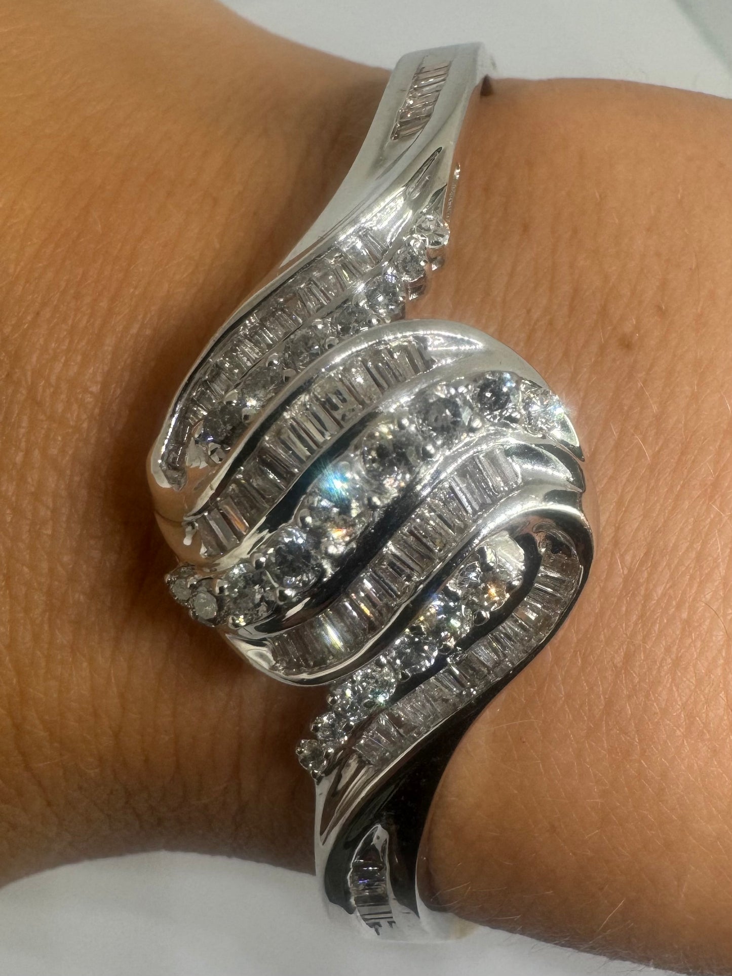 צמיד מרהיב מזהב לבן 14 קראט, בעיצוב גלים דינמי המשובץ בשיבוץ מרוכב של יהלומים עגולים ובחיתוך באגט.