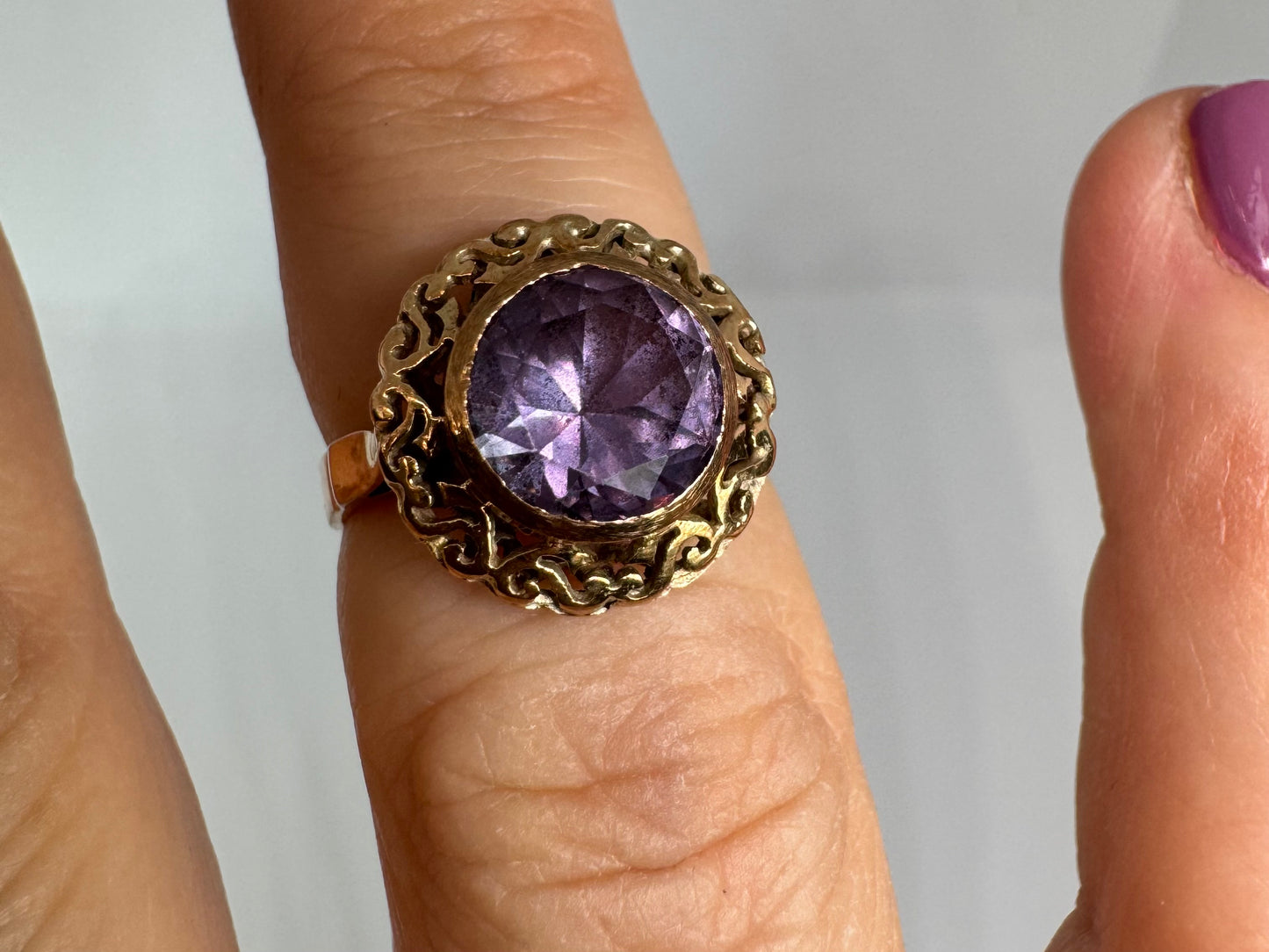 14K gold ring set with a large round-cut Tanzanite framed by an ornate filigree bezel