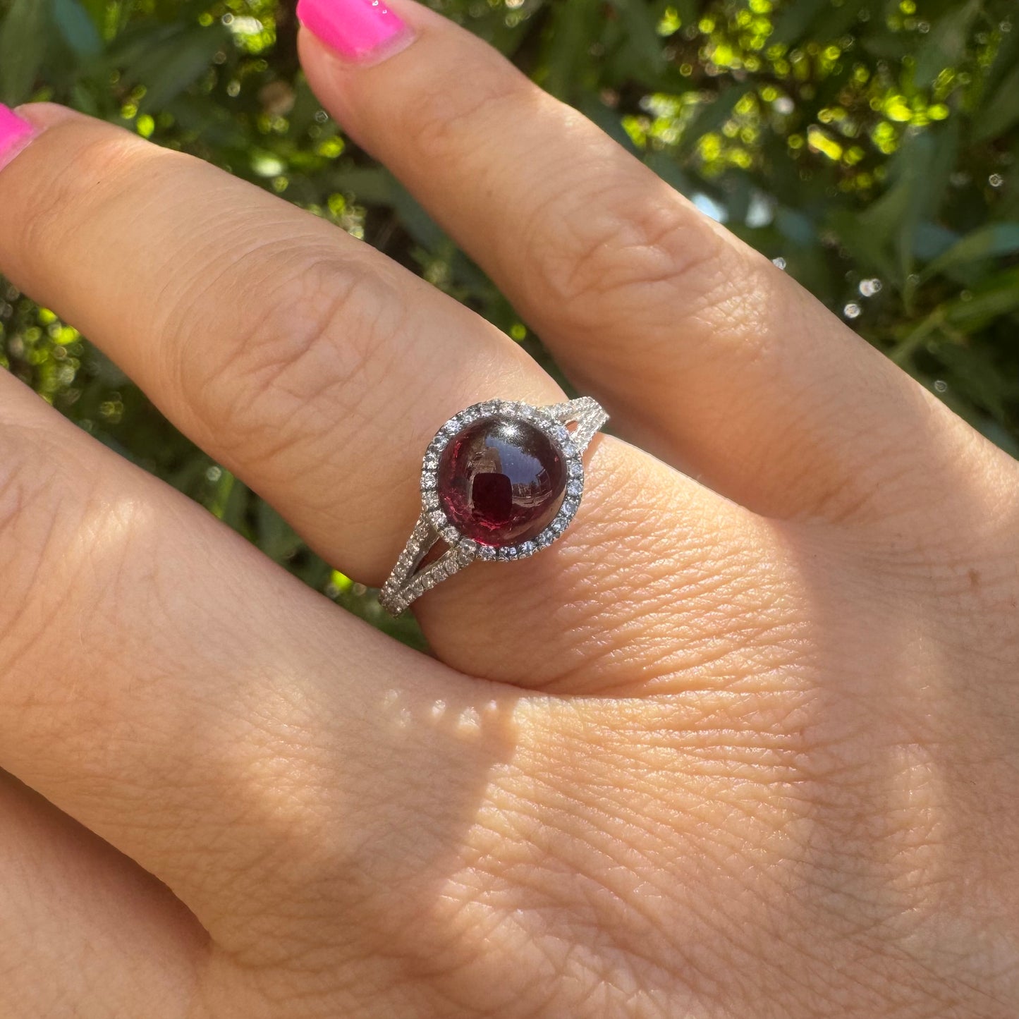 14K gold ring set with a deep red cabochon Garnet, surrounded by a halo of sparkling Diamonds